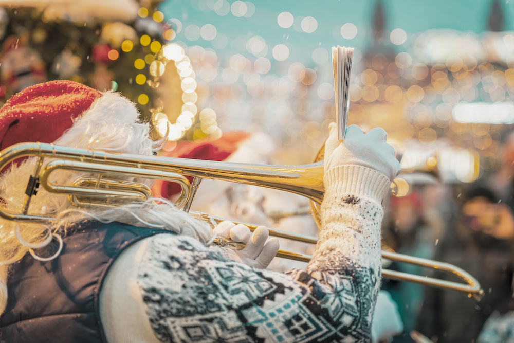 person dressed as santa marching in christmas parade, playing instrument