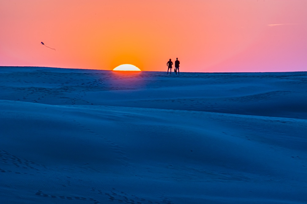 couple watching a kite fly at Jockey's Ridge State park at sunset