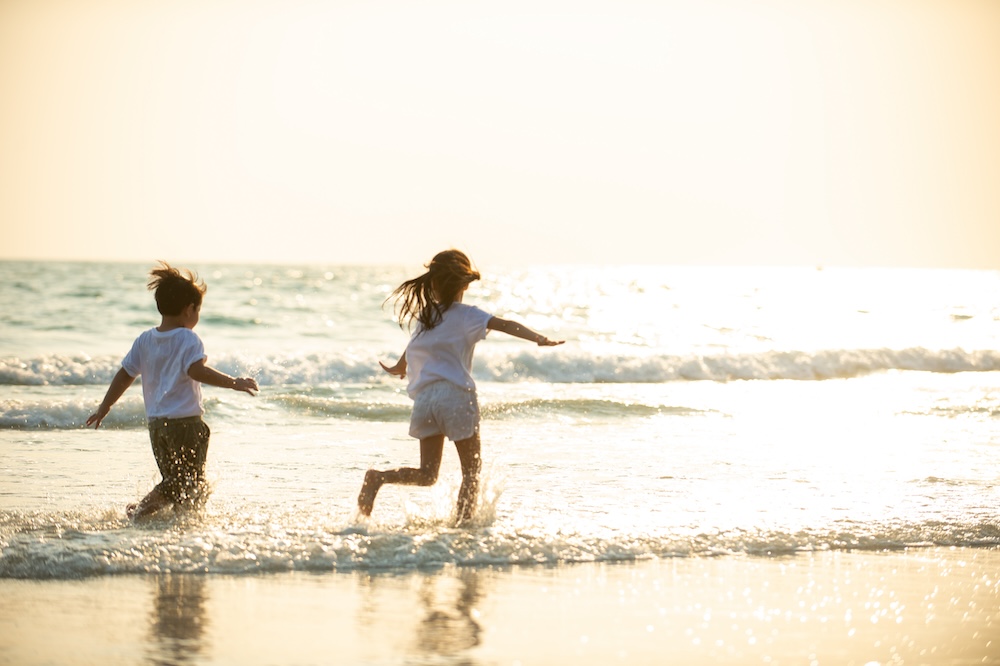 kids running on beach at sunset