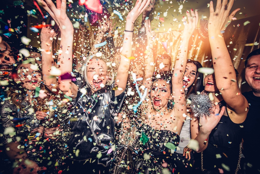 People celebrating New Years with confetti falling all around them as they dance
